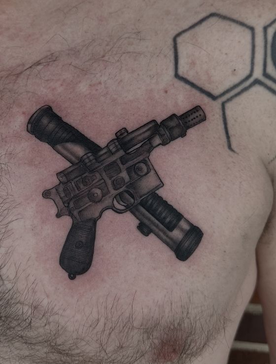 Black and grey crossed sci-fi blasters tattoo on a chest
