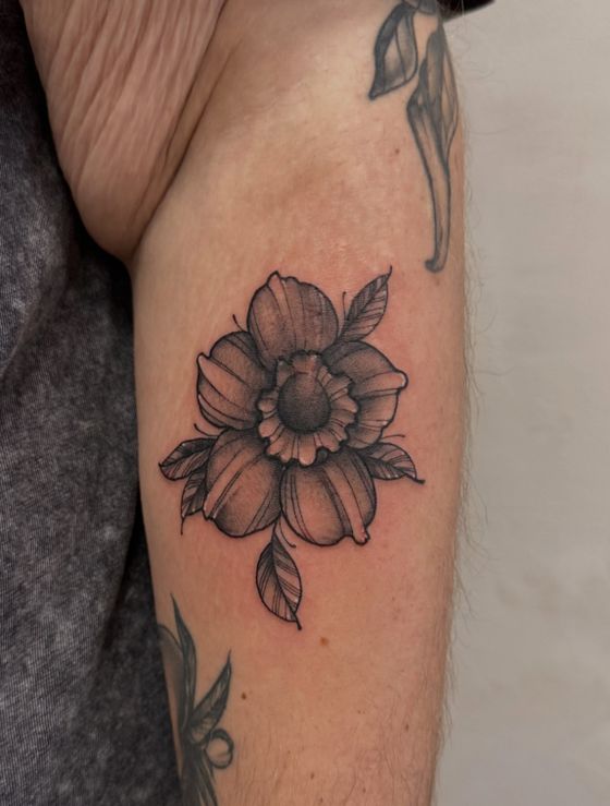 Black and grey flower tattoo on an upper arm