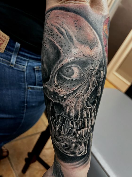 Black and grey horror skull tattoo on a forearm