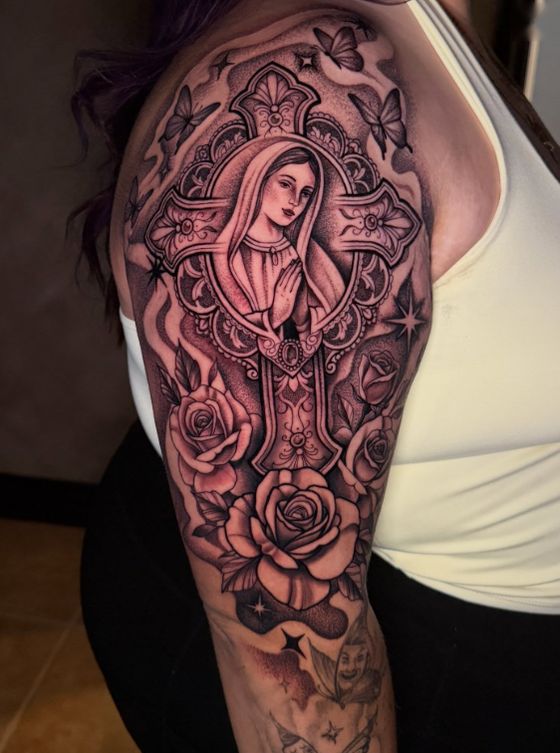 Black and grey tattoo sleeve with a praying figure, cross and roses