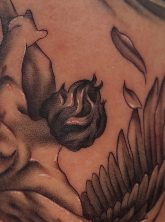 Realistic winged figure with flames tattoo in warm black and grey